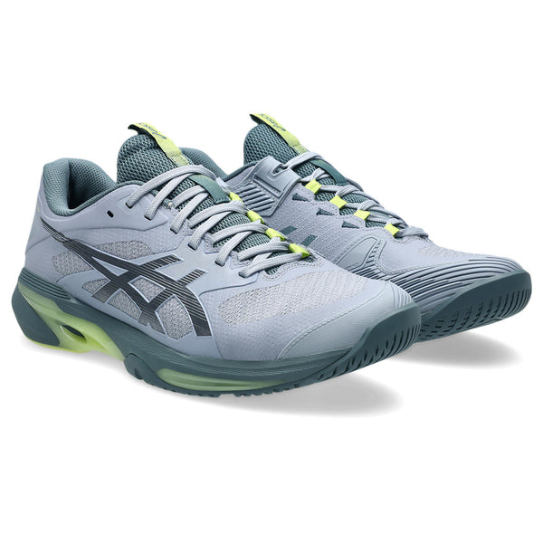 Gray ASICS tennis shoes with green accents on a white background