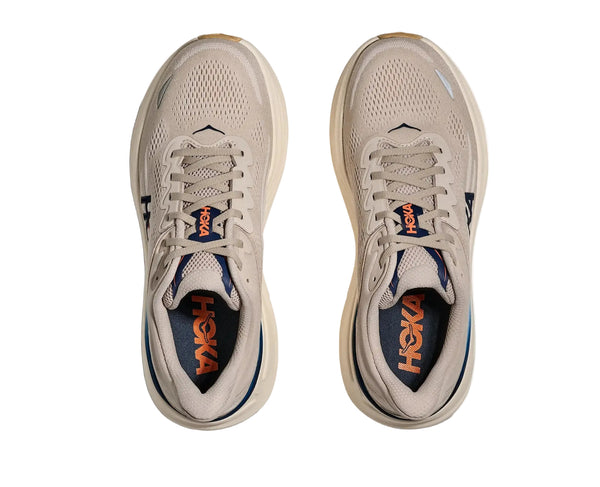 Pair of beige running shoes with 'Hoka' branding on a white background