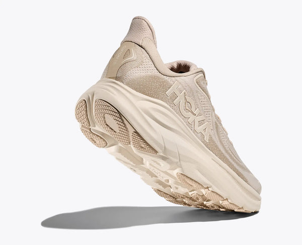Beige sneaker with brand logo on a white background with a view of most of the outsole