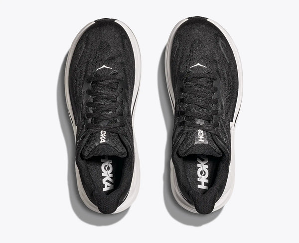 Black running shoes with white soles on a light gray background