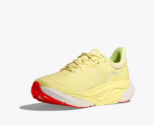 Bright yellow womens running shoe with red outsole on a white background