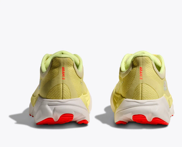 The heel area of these yellow running shoes with red accents on a white background