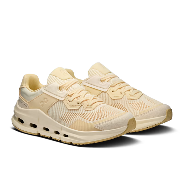 A pair of low-top athletic sneakers in a monochromatic cream and light tan colorway, featuring a mesh upper, hook-and-loop strap closure, and thick cushioned midsoles, shown on a plain white background.