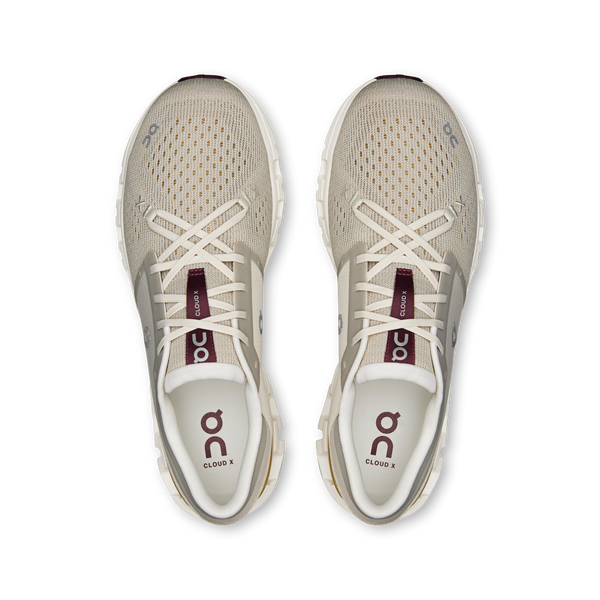 Pair of beige running shoes with white soles on a white background