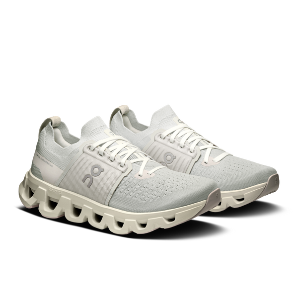 Pair of light gray running shoes with unique sole design on a white background