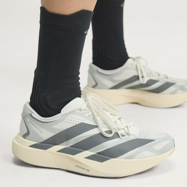 A close up of an adidas running shoe and black socks.