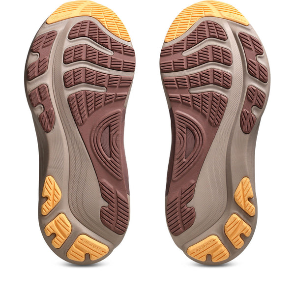 Close-up of a pair of brown and yellow running shoes with tread pattern on a white background
