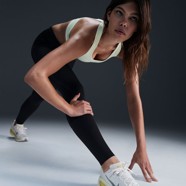 Woman in athletic wear preparing to run on a dark background