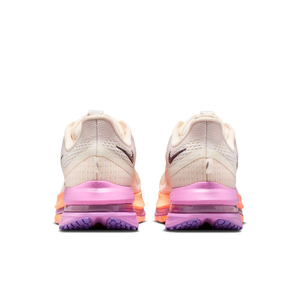 Pair of running shoes with a pink and orange sole on a white background