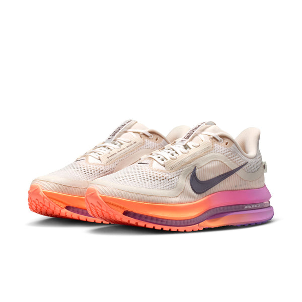 Beige running shoes with orange and purple sole on a white background