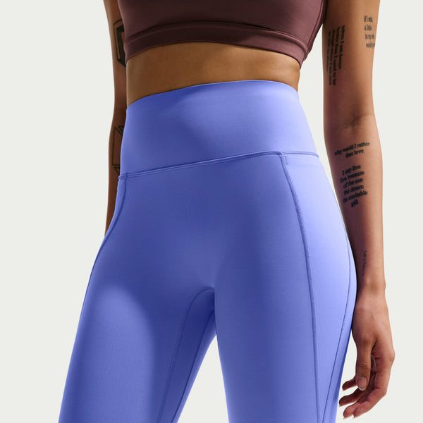 Person wearing blue leggings and a brown sports bra on a light gray background