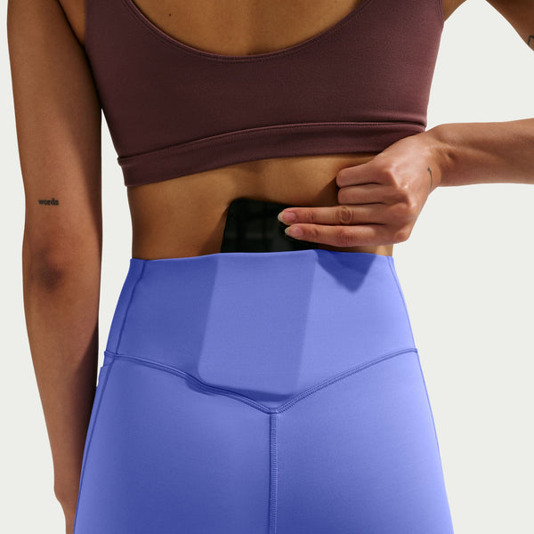 Person wearing a maroon sports bra and blue leggings on a light gray background