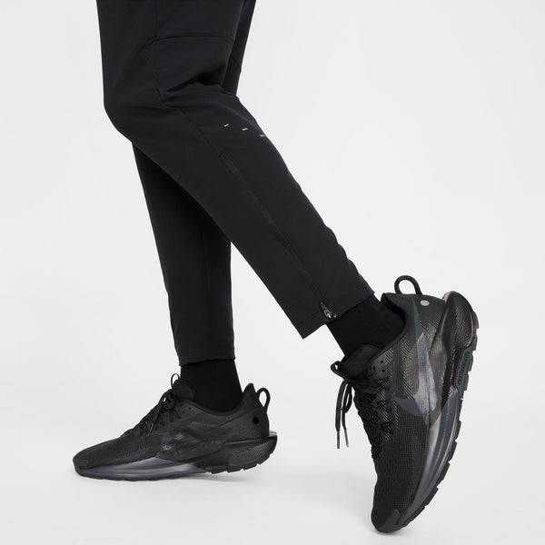 Black athletic shoes worn with black pants on a white background
