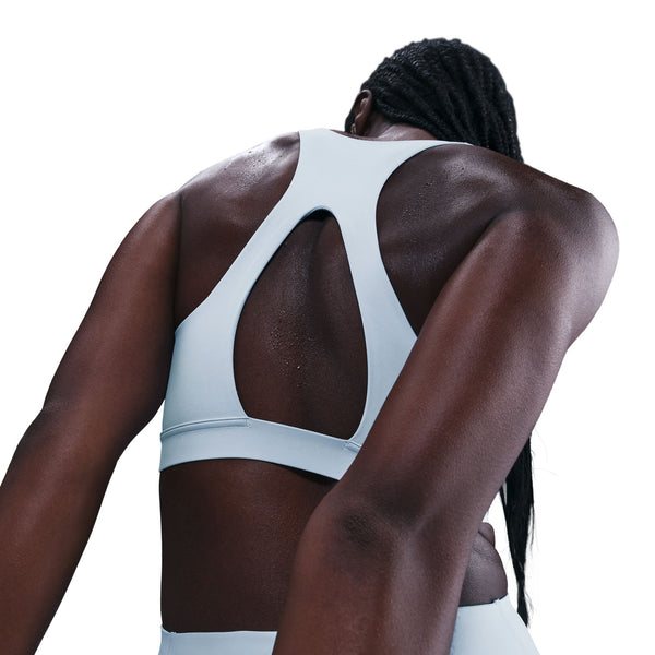 Person wearing a light gray sports bra with a white background