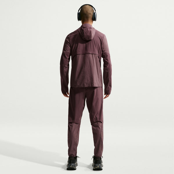 Person wearing a maroon tracksuit and headphones on a white background