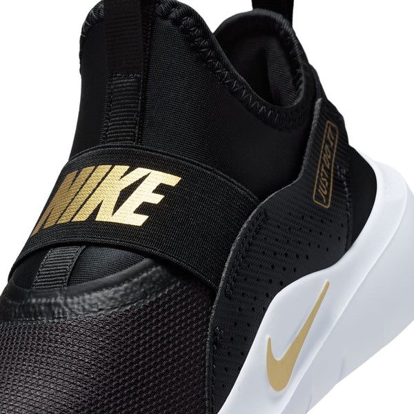 Close-up of a Nike sneaker in black with metallic gold branding and a white midsole, showing the side strap and Swoosh.