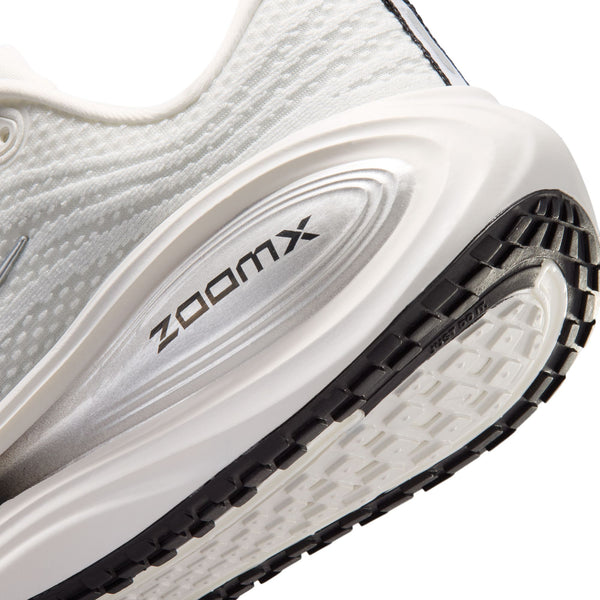 Close-up of a white athletic shoe with 'zoomx' branding on the sole.