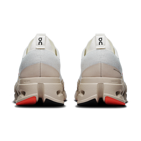 Back view of beige running shoes with red accents on a white background.