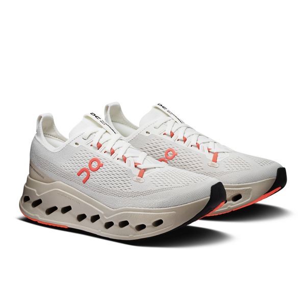 Pair of white running shoes with orange accents on a white background.