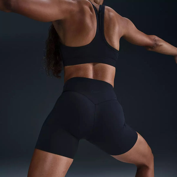 Person wearing a black sports bra and shorts on a dark background