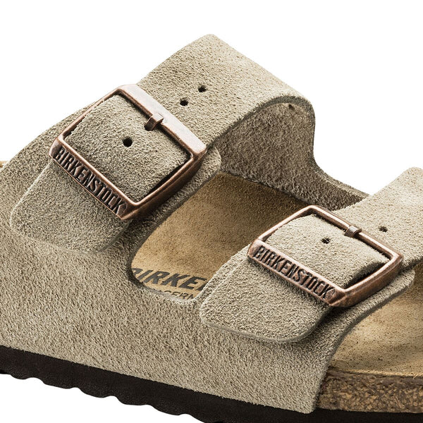Close-up of a beige suede sandal with brown leather straps on a white background