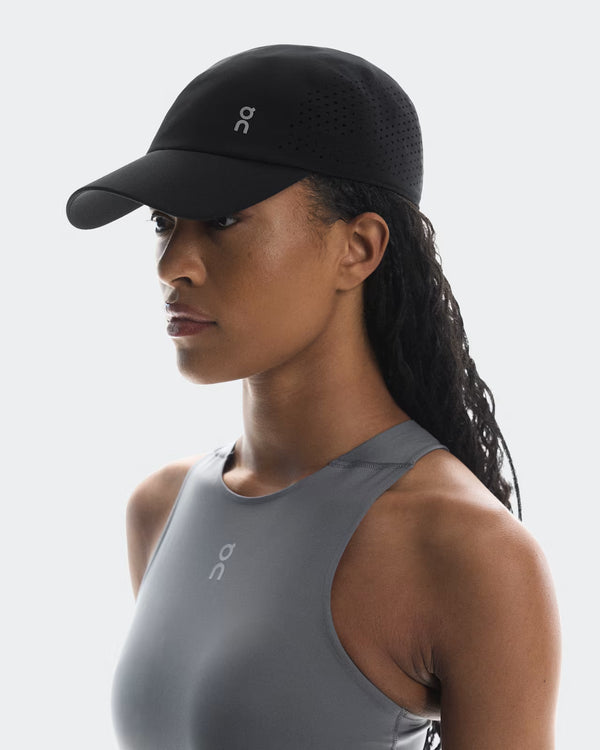 Woman wearing a black cap and gray tank top on a white background