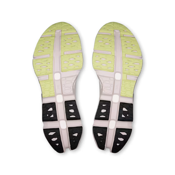 The outsoles of a pair of running shoes, showing a light yellow-green top section with ventilation holes, a pale pink midsole, and black and white rear stabilizers.