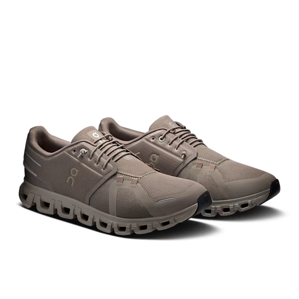 A pair of On running shoes in a taupe brown colorway, featuring a breathable mesh upper, lace-up closure, and a distinctive chunky segmented sole, shown against a plain white background.