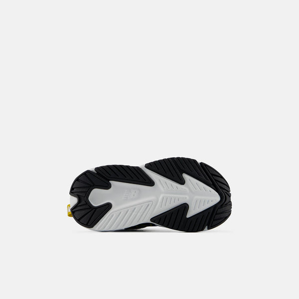 A close-up of a sneaker's black and white textured outsole, showing the tread pattern and a small yellow pull tab on a light gray background.