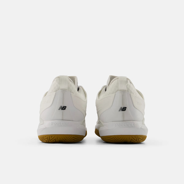 A pair of New Balance court shoes shown from the back, featuring an off-white leather upper and a brown gum sole, set against a light gray background.