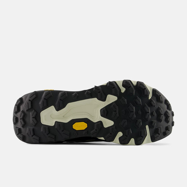 Close-up of a black and beige outsole with a yellow dot on a white background