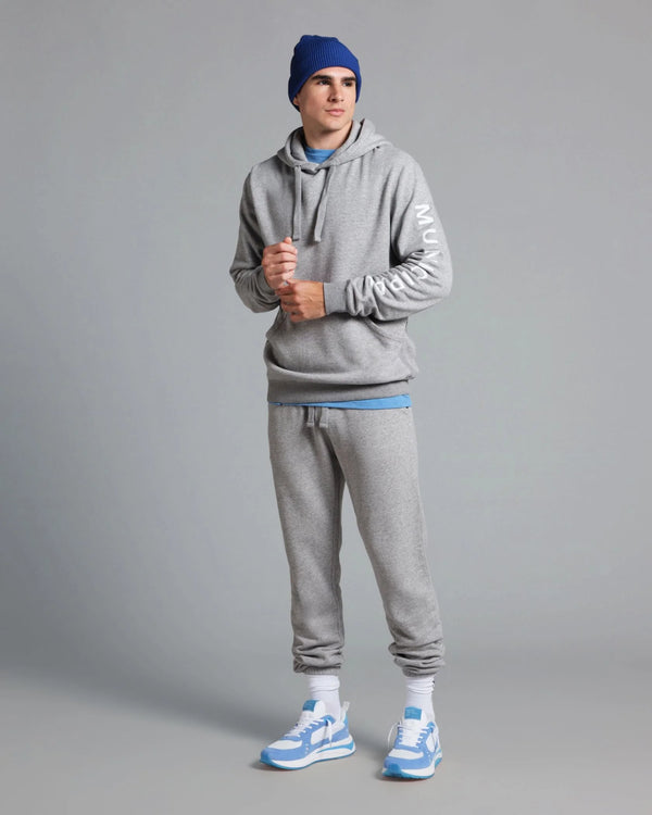 Person wearing a gray hoodie and jogger set with blue accents on a gray background