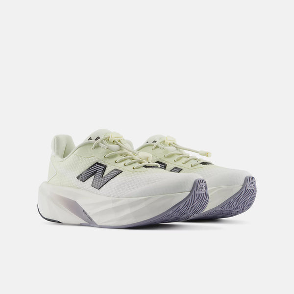 A pair of New Balance running shoes in a light cream and pale yellow-green colorway, featuring dark gray 'N' logos and textured gray soles, set against a plain light gray background.