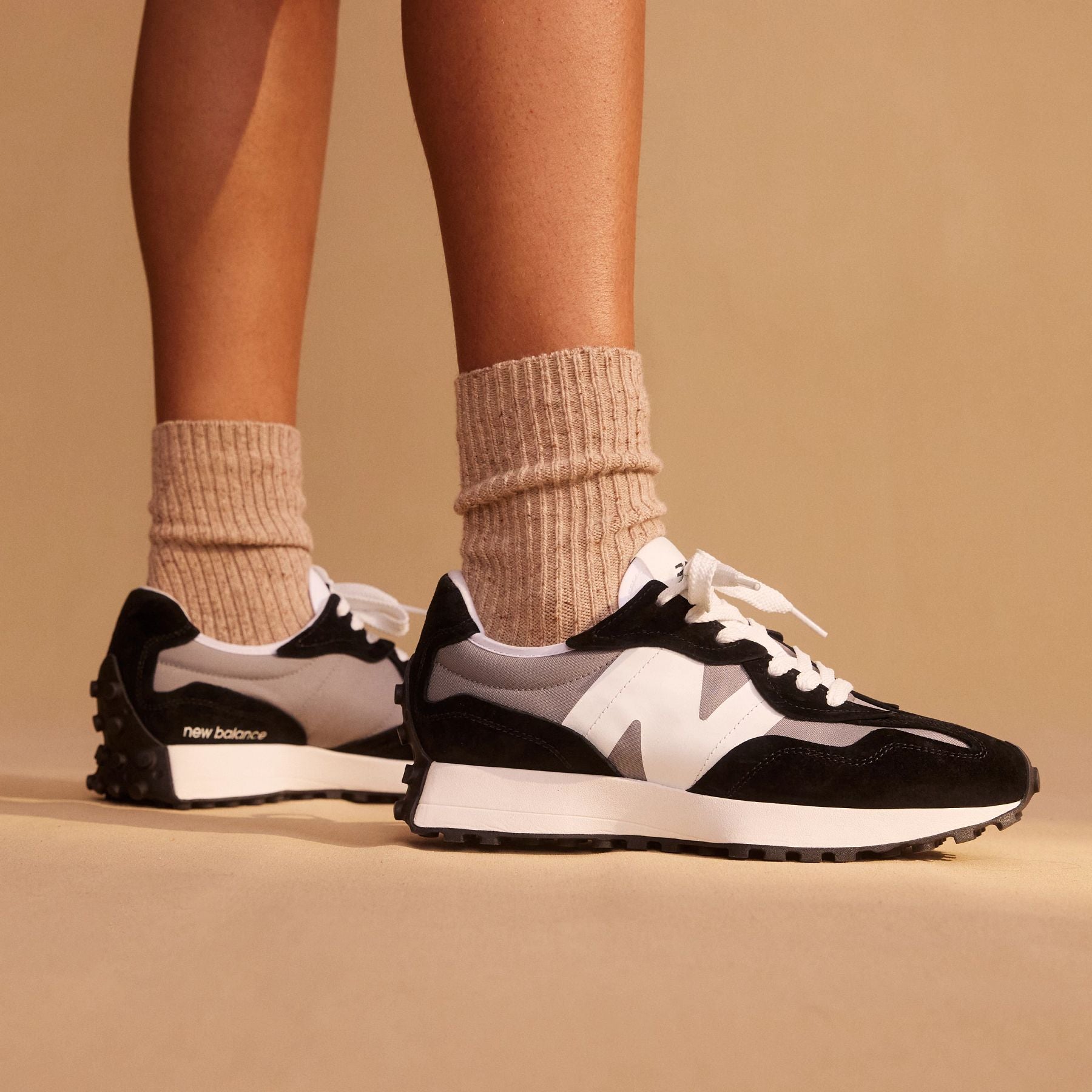 View of a model wearing the Men's New Balance 327 lifestyle shoe in Black/Grey