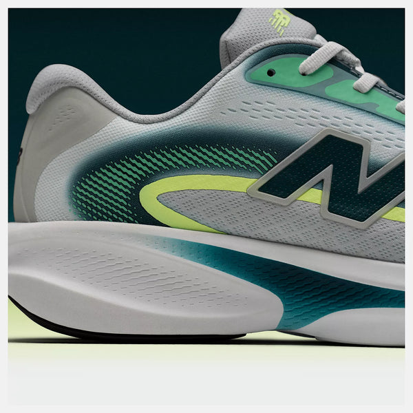 Gray and green NB athletic shoe with brand logo on a dark background