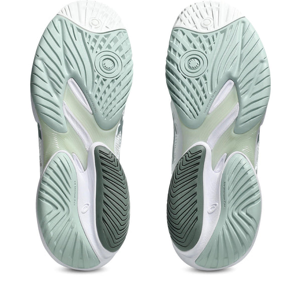 Close-up of green and white athletic shoes with tread pattern on a white background