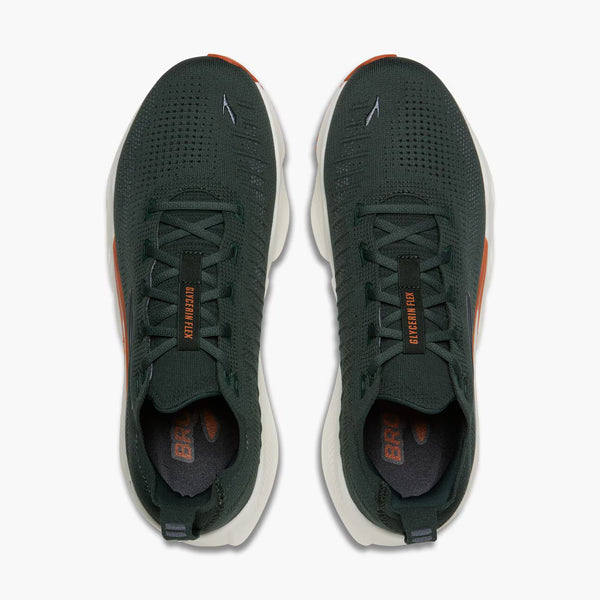 A pair of Brooks Ghost 15 running shoes in dark forest green with orange accents and a white midsole, shown from a top-down view on a light gray background.
