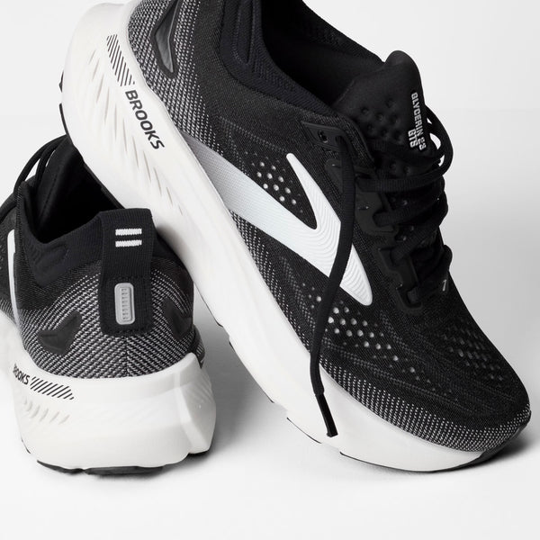 Black and white running shoes with 'Brooks' branding on a light gray background