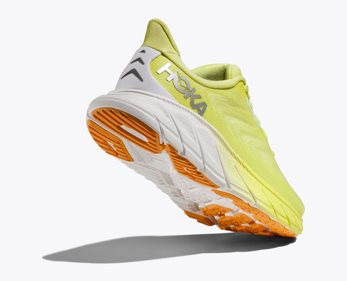 Back angle view of the Women's Arahi 6 by HOKA in the color Citrus Glow/White
