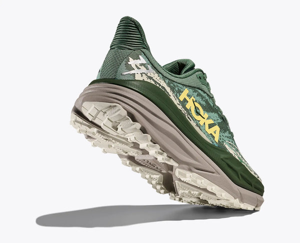 Green running shoe with 'Hoka' branding on a white background