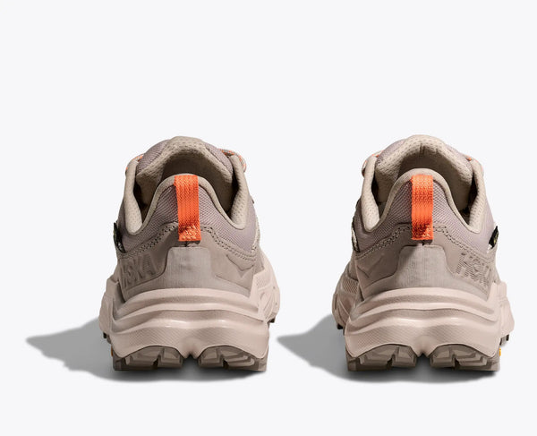 Pair of beige hiking shoes with orange accents on a white background