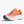 Coral colored trail unning shoe with green and white accents on a light gray background