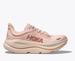Pink rose latte colored running shoe with 'Hoka' branding on a white background
