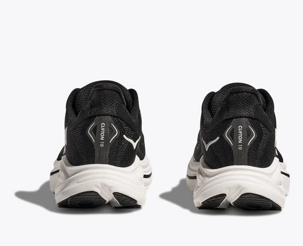 Black running shoes with white soles on a light gray background