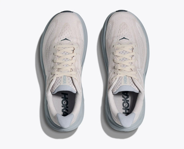 Pair of white running shoes with visible Hoka branding on a light gray background