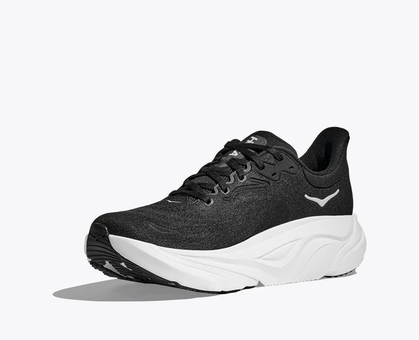 Medial side of a black Hoka running shoe with white sole on a light gray background