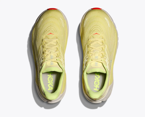 Pair of yellow running shoes with 'Hoka' branding on a white background