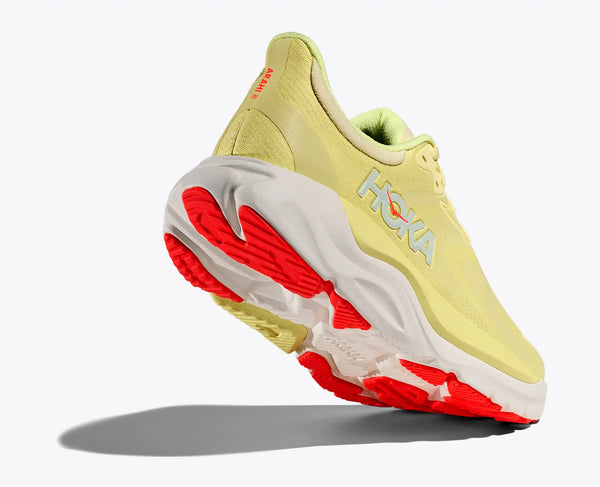 Yellow running shoe with red sole on a white background