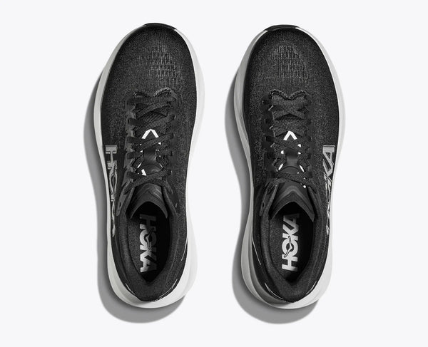 A pair of mens hoka running shes with a black upper and a white midsole with the brand name appearing on the heel portion of the sock liner.
