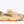 Light butter colored running shoe with red accents on a white background